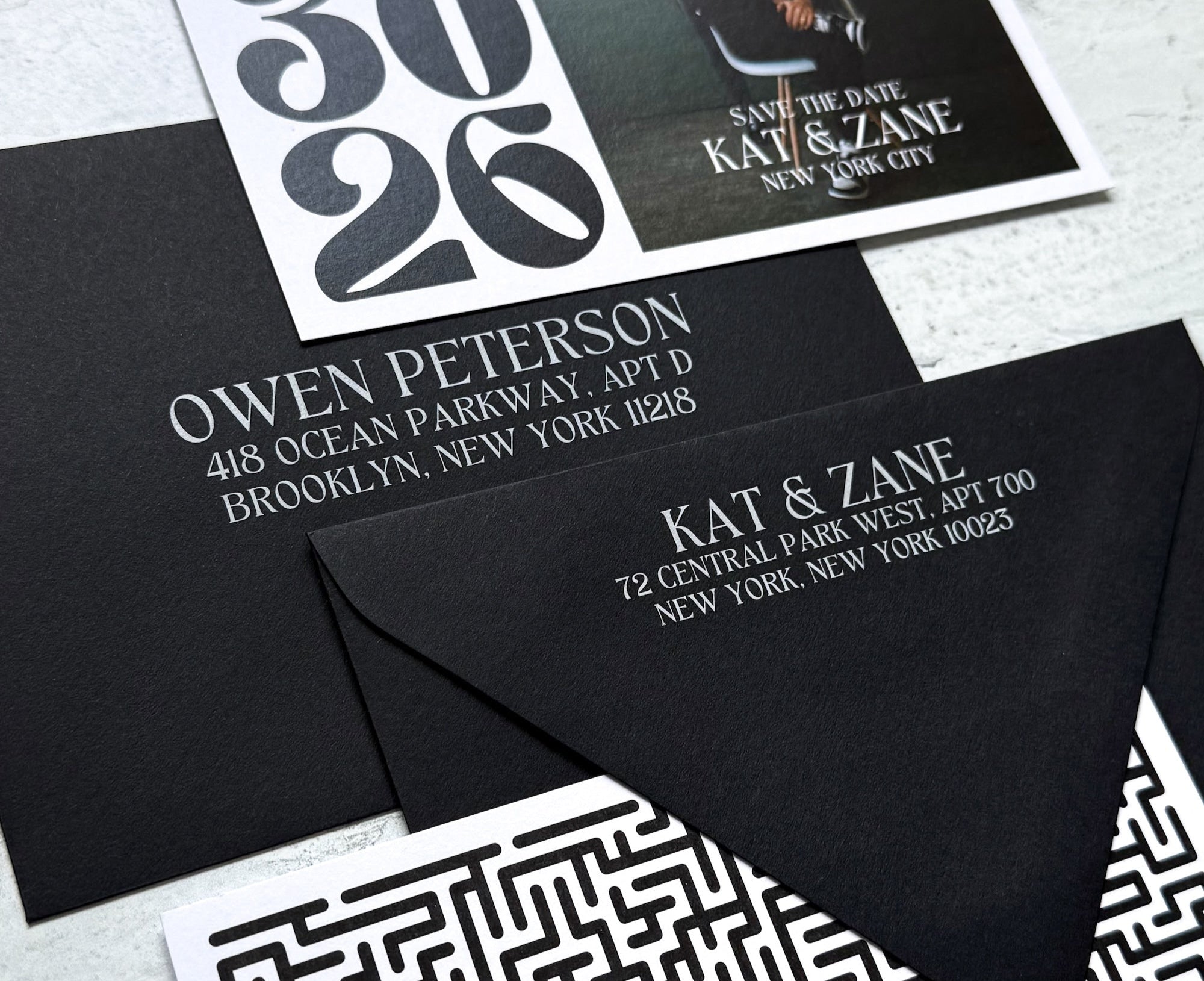 Black and white stationery set with envelopes and cards on a light gray surface.